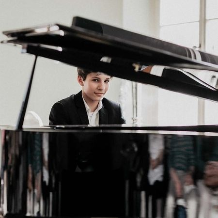 Ein Mann im Anzug spielt ein Konzert auf einem Flügel.