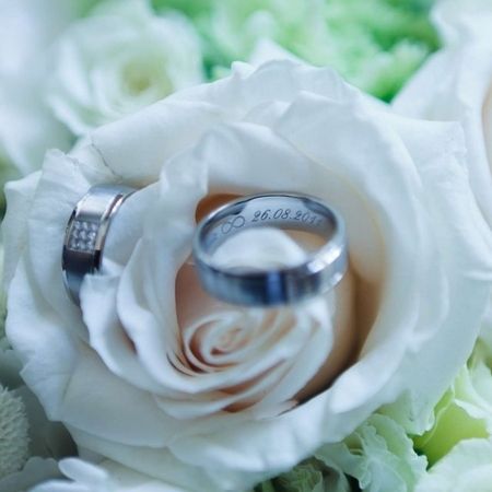 Zwei Eheringe liegen auf einem Strauß aus weißen Blumen, symbolisieren Liebe und Verbundenheit.