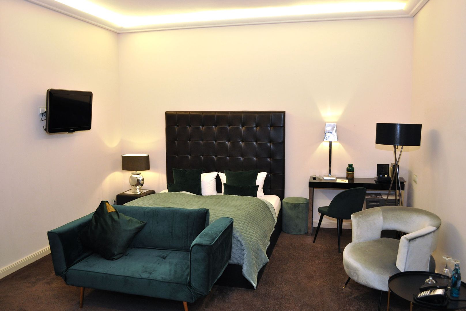 Ein Schlafzimmer mit einem Bett, einem Stuhl und einem Fernseher, das eine gemütliche Atmosphäre ausstrahlt.